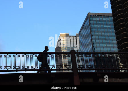 La figure d'un piéton est silhouetté contre le ciel sur leur trajet du matin alors qu'ils traversent le pont de State Street à Chicago. Banque D'Images