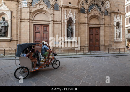 Florence, Italie - 2018, 14 juillet : les touristes sur une visite guidée, sur pedicab, visiter l'église Orsanmichele, dans le centre historique de Florence, Italie. Banque D'Images