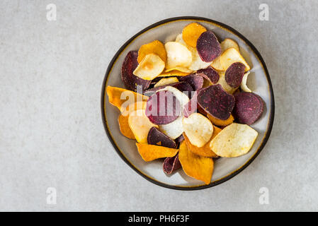 Bol de collation saine de croustilles de légumes, tels que la patate douce, betterave, carotte, panais sur fond gris clair Banque D'Images
