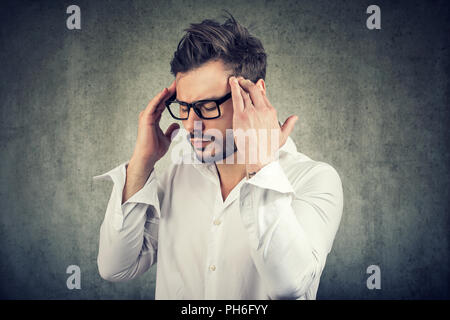 Homme adulte dans les griffes de lunettes sur les temples d'essayer de se concentrer sur la prise de décisions Banque D'Images