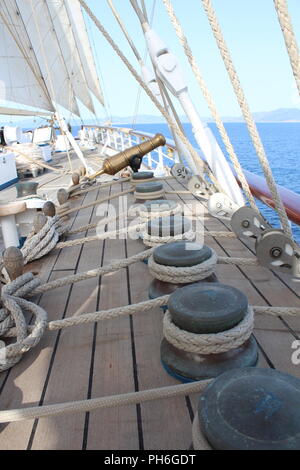 Pont principal d'un clipper ship montrant un canon en laiton avec une corde, détenteurs de cabillots et montage Banque D'Images