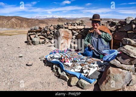 Une dame andine vend des articles pour touristes sur une route dans la région de Uyuni en Bolivie Banque D'Images