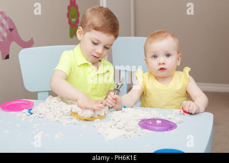 Portrait de groupe de deux frères mignon enfants jouant ou sable cinétique de la pâte à modeler ensemble dans le jardin. Début de la créativité le développement du cerveau concept. L Banque D'Images