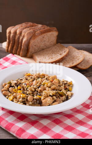 En toutes lettres, pois chiche, thon et salade de maïs disposés sur table rustique avec du pain Banque D'Images