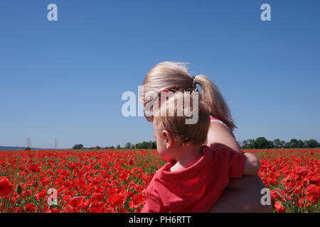 Maman avec son enfant dans des champs de coquelicots Banque D'Images