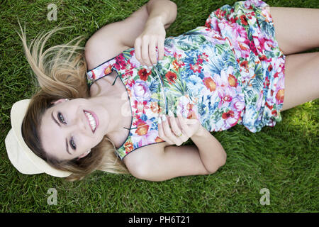 Smiling Pretty Young Woman Lying on les graminées Banque D'Images