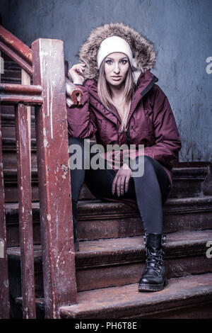 Cute woman in winter coat on staircase Banque D'Images