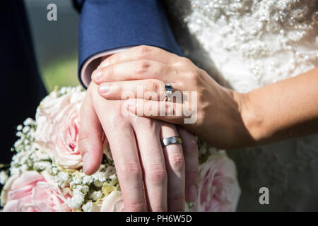 Close up de la mariée et se toilette mains avec leurs doigts sur des bandes de mariage Banque D'Images