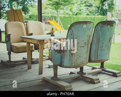 Vintage fauteuils avec table en bois sur plancher en bois sur green park historique en style retro cafe. Mix and Match unique de style meubles concept. Banque D'Images