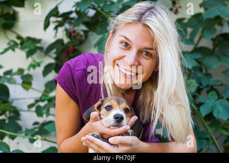 Happy blonde woman cuddling avec mignon chiot beagle. L'amour pur Banque D'Images