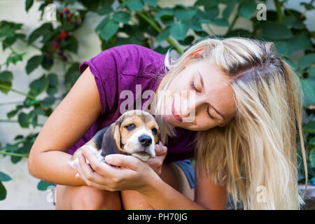 Happy blonde woman cuddling avec mignon chiot beagle. L'amour pur Banque D'Images