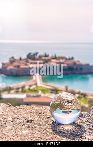 Sveti Stefan, le Monténégro - Avril 2018 : vue vieille ville historique se reflète dans une grande boule de verre transparent Banque D'Images