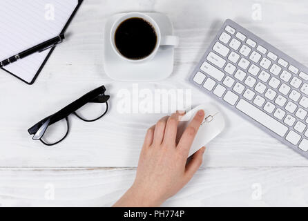 À l'aide de main de femme sur la souris de l'ordinateur de bureau blanc organisé Banque D'Images