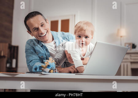 L'homme heureux mignon à la recherche après un bébé Banque D'Images