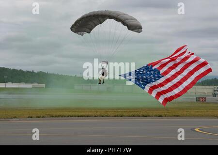 Un cavalier de sauveteurs-parachutistes de l'Alaska Air National Guard, 212e Escadron de sauvetage, des terres avec le drapeau américain le 30 juin 2018, at Joint Base Elmendorf-Richardson, en Alaska. Pour ouvrir l'Arctique 2018 Thunder Open House, membres de sauveteurs-parachutistes ont sauté d'un C-130 Hercules pendant l'hymne national, l'exécution et de l'Alaska américain drapeaux. Banque D'Images