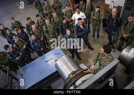 SAN DIEGO (30 juin 2018) Le Lieutenant Matthew Norton, une école d'officiers de guerre de surface Det. San Diego, l'instructeur explique la fonction de l'étanchéité du tube à l'arrière cours d'agent de la Division de base (BDOC) étudiants pendant un tour machines. Business document est un programme intensif de 9 semaines de cours d'enseignement conçu pour fournir une formation en classe de base pour d'éventuels agents de guerre de surface. Banque D'Images