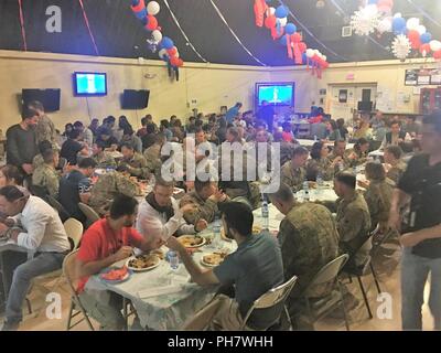 Des entrepreneurs afghans et des soldats de former, conseiller et assister les Command-South, composé de la 40e Division d'infanterie, la Garde nationale de Californie, et l'équipe de combat de la 2e Brigade d'infanterie, 4e Division d'infanterie, profiter de la nourriture traditionnelle afghane au cours au cours de l'Eid al-Fitr, une fête, à l'aérodrome de Kandahar, Afghanistan, le 18 juin. L'Eid al-Fitr, qui porte le nom d'Eid, est une célébration marquant la fin du Ramadan, connu localement sous le nom de Ramazan, le mois saint de l'Islam du jeûne. Banque D'Images