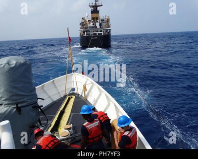 Les équipages des garde-côtes de la WLB (Noyer) 205 et Oliver Berry (WPC 1124) procéder à un ravitaillement en mer 'arrière' Juin 24, 2018, dans les environs de l'atoll de Johnston, une possession des États-Unis dans l'océan Pacifique. Oliver Berry a reçu de carburant pour aider à achever un noyer 2 500 milles marins à partir d'Hawaï de transit aux Îles Marshall. Banque D'Images