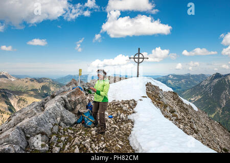 Female hiker se lit dans le guide de randonnées, sommet des Seekarspitz avec sommet cross, Tyrol, Autriche Banque D'Images