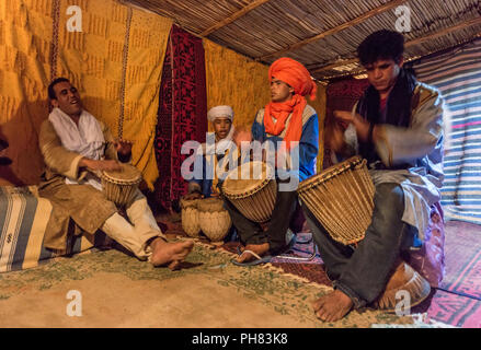 Avec les vêtements traditionnels bédouins jouer à la batterie dans une tente, l'Erg Chebbi, Merzouga, Sahara, Maroc Banque D'Images