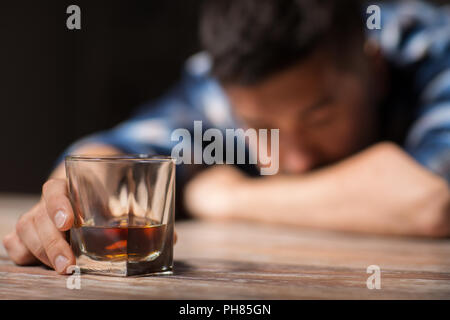 L'homme ivre avec verre d'alcool sur la table de nuit Banque D'Images