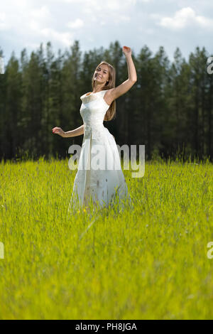 Jeune fille dans une robe de mariage de sourire et de danser Banque D'Images