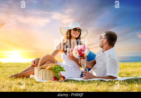 Couple avec fleurs drinking champagne at picnic Banque D'Images