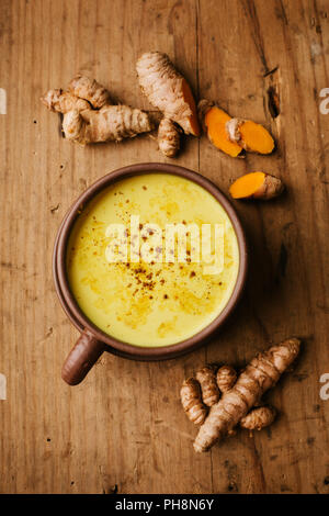 Snacks curcuma curcuma lait dans tasse sur la vieille table en bois. Organisé avec les racines de curcuma et d'épices. Vue de dessus Banque D'Images