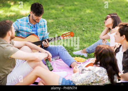 Les amis à jouer de la guitare à pique-nique au parc d'été Banque D'Images