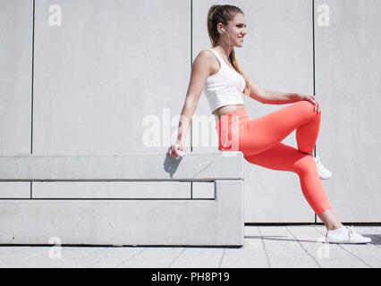 Jolie femme en tenue de sport assis sur le banc Banque D'Images