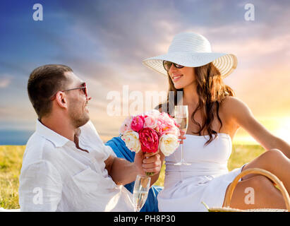 Couple avec fleurs drinking champagne at picnic Banque D'Images