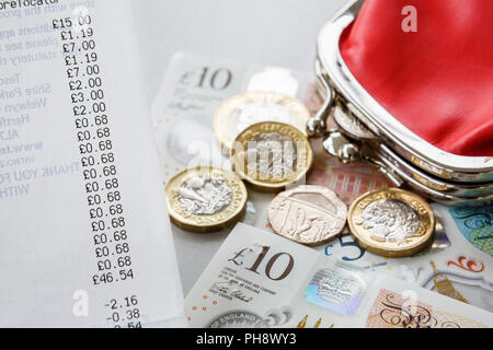 Supermarché shopping jusqu'à réception avec de l'argent Sterling pièces et billets de livre et un sac rouge d'argent. Angleterre, Royaume-Uni, Grande-Bretagne Banque D'Images