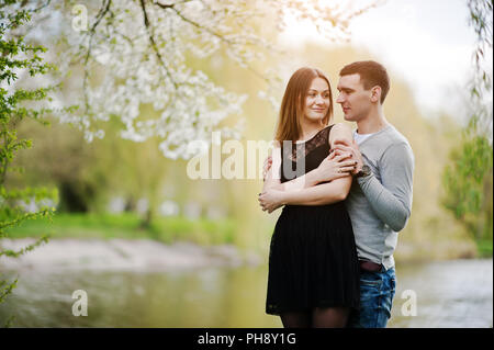 Jeune couple dans l'amour d'arrière-plan de plein air lac avec blossom tree Banque D'Images