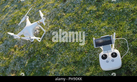 Drone quadcopter blanc avec télécommande sur une herbe verte Banque D'Images