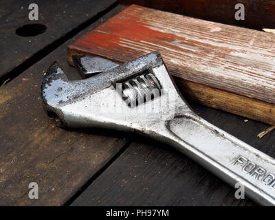 Une clé à molette (clé réglable) portant sur une vieille boîte à outils en bois. Banque D'Images