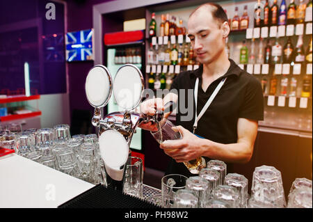 Barman verse une bière au bar au club Banque D'Images