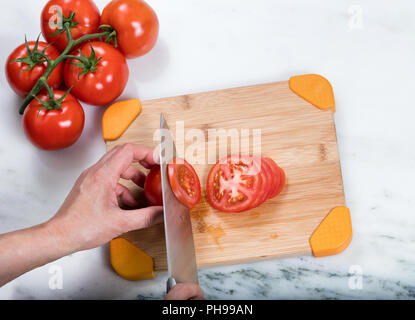 Le tranchage main frais jardin tomates sur une planche à découper en bambou naturel Banque D'Images