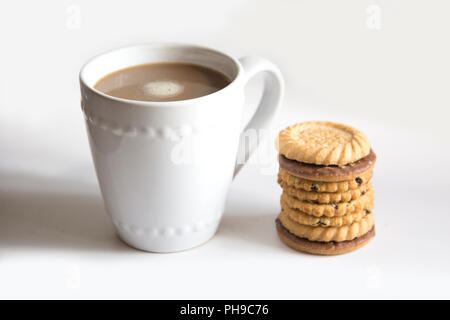 Une tasse de café dans un mug blanc sur un fond blanc avec une pile de biscuits empilés à côté de la tasse Banque D'Images
