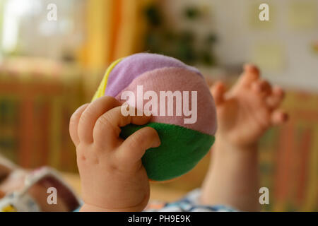 Les mains de bébé jouant avec une balle molle - close up Banque D'Images