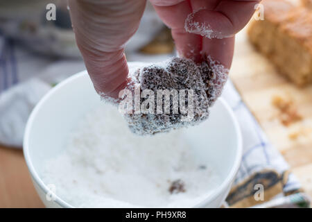 Les mains des femmes faisant de la farine de coco brownies Banque D'Images