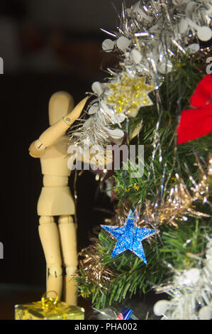 Un mannequin en bois équitation l'arbre de Noël avec des guirlandes. Banque D'Images