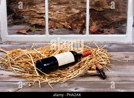 Unopen bouteille de vin rouge sur la paille avec opener Banque D'Images