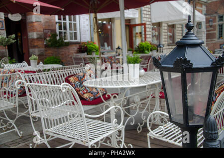 Lampadaire Vintage dans le contexte de l'ancienne terrasse de café dans la vieille ville, Gdansk, Pologne. Pas de personnes. Des tables et des chaises métalliques sur une vieille Banque D'Images