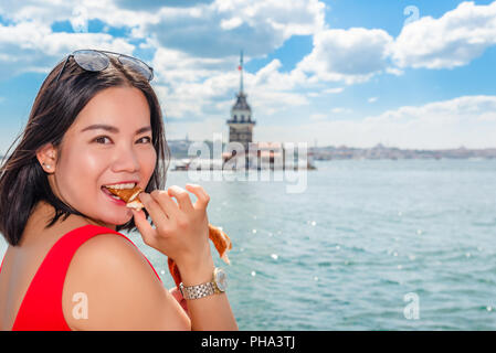 Belle femme chinoise mange simit turc traditionnel bagel) (en face de tour de la jeune fille à Istanbul, Turquie Banque D'Images