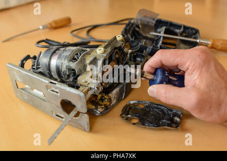 Plumber repairing broken jigsaw avec tournevis, close-up Banque D'Images