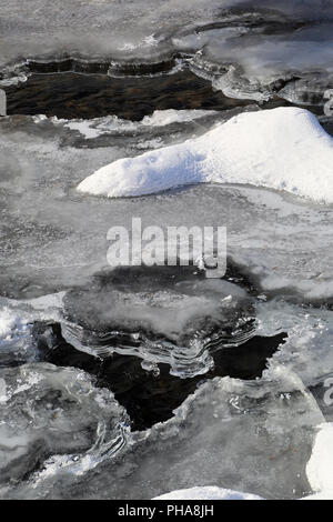 Glace et neige sur une rivière qui dégèle Banque D'Images