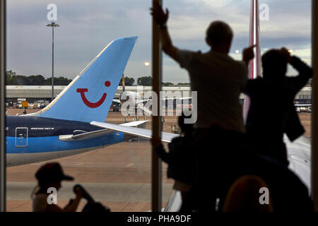 Boeing 787-8 Dreamliner TUI Airways à l'aéroport de Manchester en famille voir la piste de l'intérieur de la fenêtre de terminal Banque D'Images