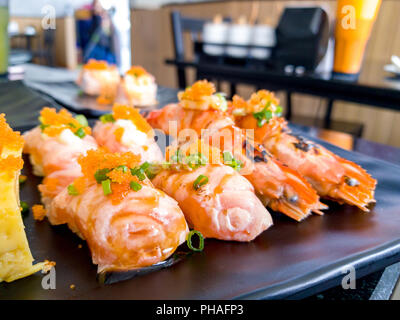 Le feu brûler Crevettes Sushi Aburi (crevettes) et de la rivière au saumon avec sauce sushi Aburi et Sandwich Tamagoyaki mis sur une plaque noire dans un restaurant japonais. Banque D'Images