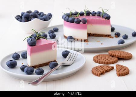 Les deux couleurs mini bleuets gâteau au fromage. Sans cuisson ronde cheesecake, partie découpée sur la petite plaque avec quelques cookies dans le focus. Haut de gâteau décorer Banque D'Images