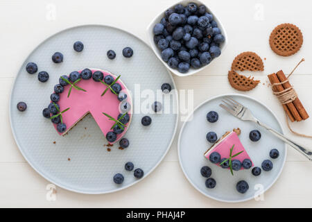 Les deux couleurs mini bleuets gâteau au fromage. Sans cuisson ronde cheesecake, partie découpée sur la petite plaque avec quelques cookies dans le focus. Haut de gâteau décorer Banque D'Images